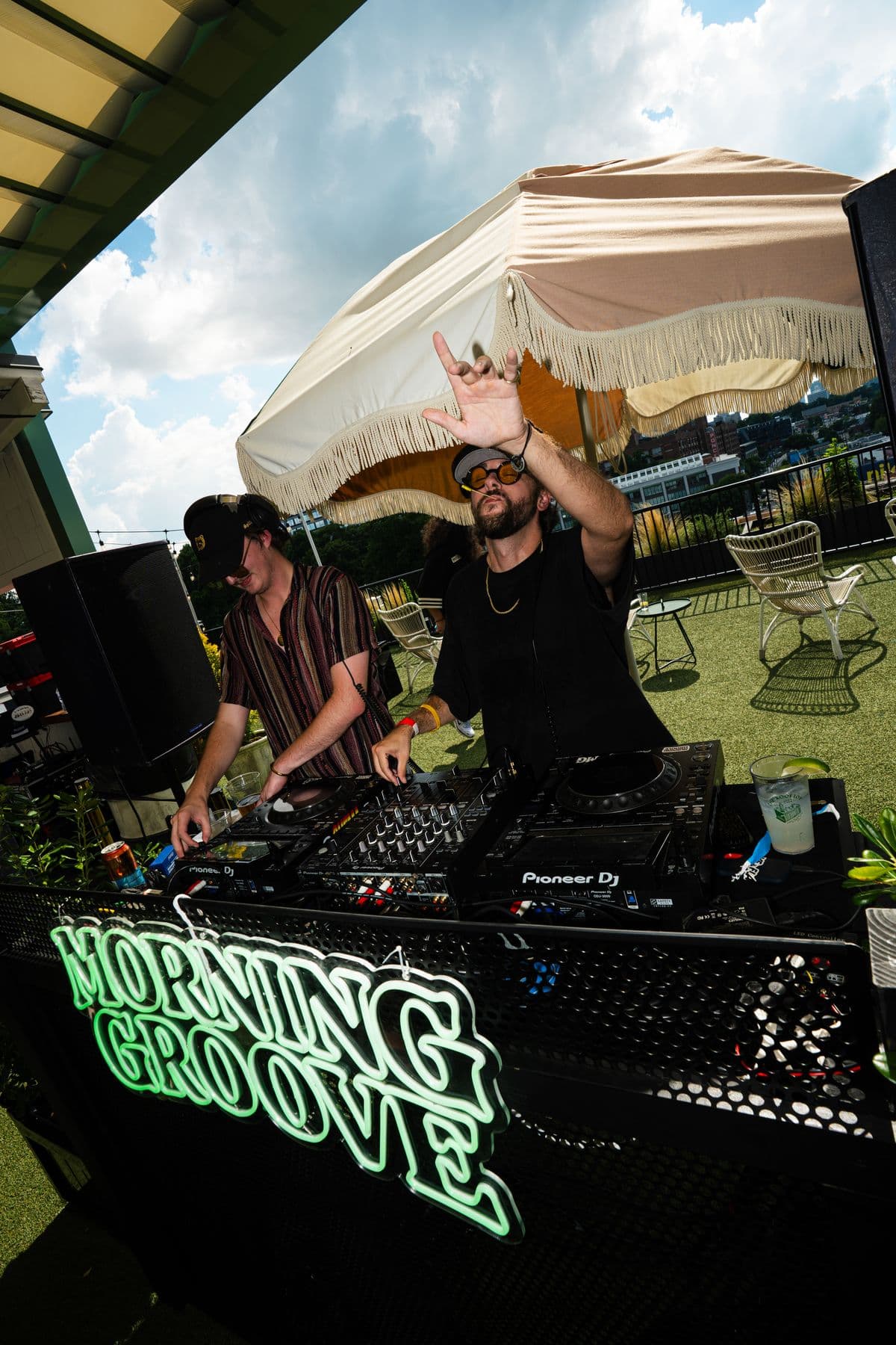 The DJ booth under a fringed umbrella, green Morning Groove neon glowing